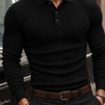 Man in a tight black ribbed polo shirt and black trousers by a car.
