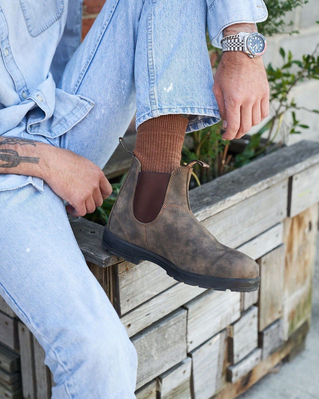 Brown leather Chelsea boots paired with light blue denim jeans and brown socks.