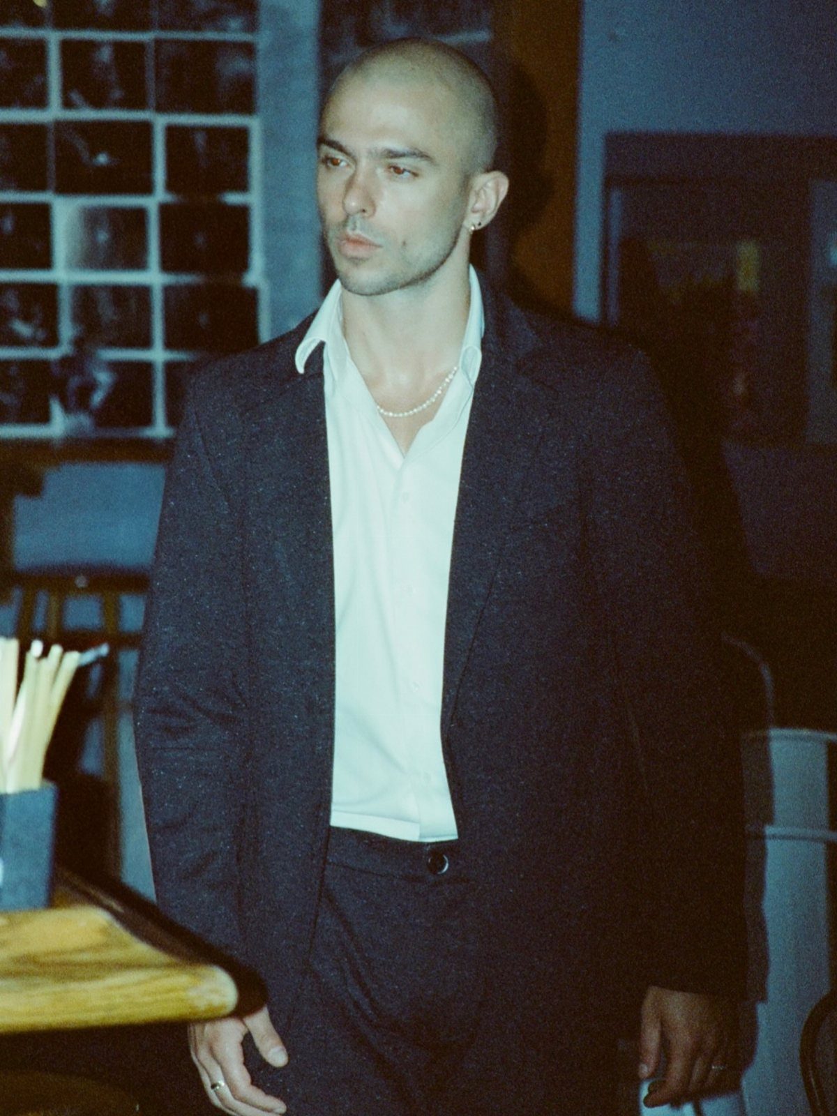 Bald man in a navy blazer and white shirt at a jazz club.
