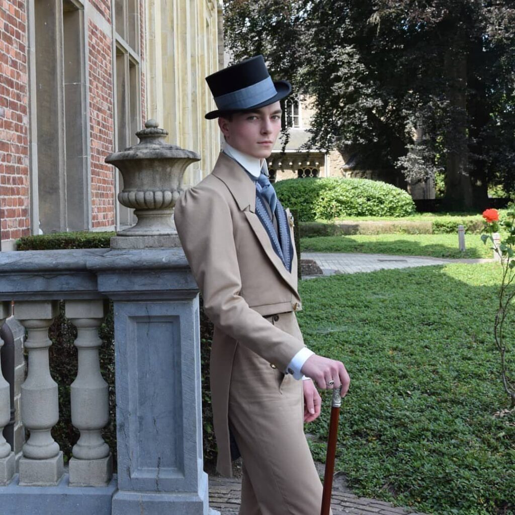 Man in tan tailcoat and black top hat leaning on stone balustrade.