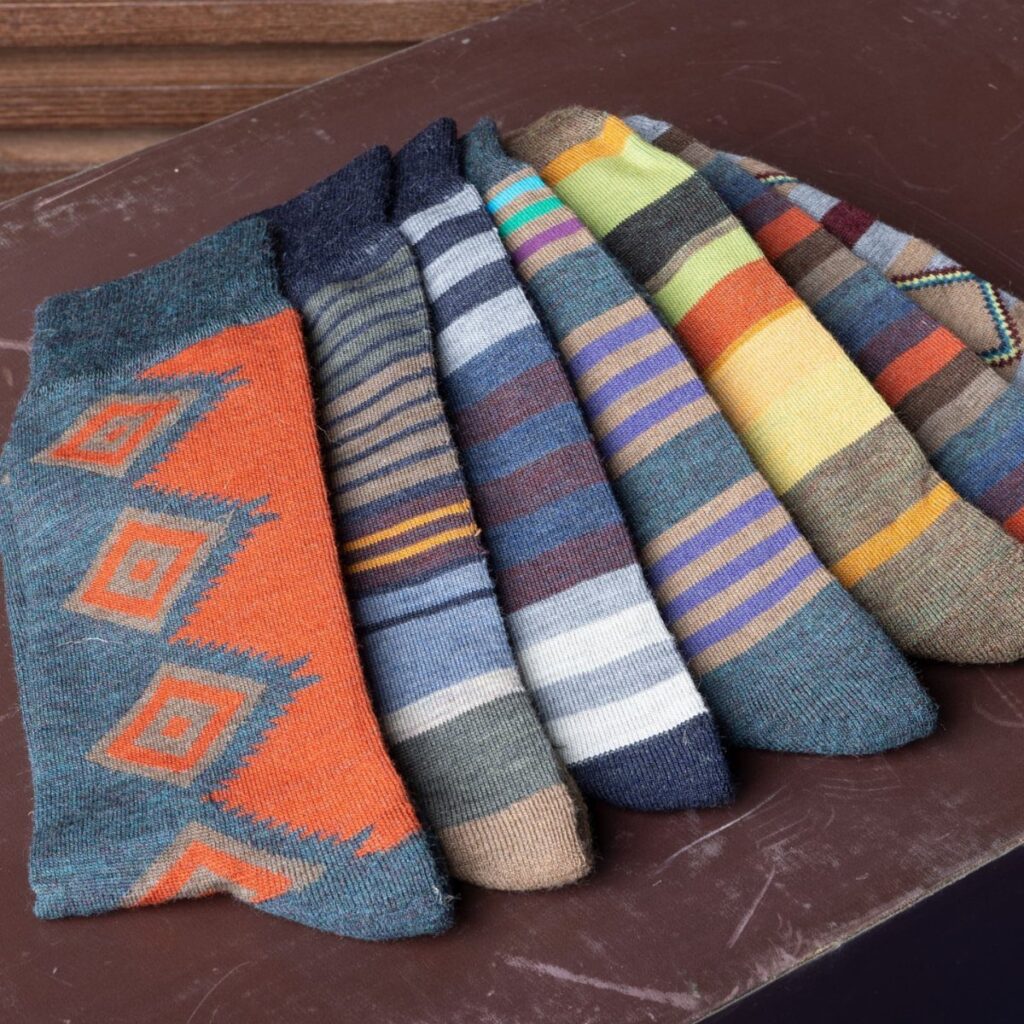 Patterned wool socks in various colors and stripes laid on a brown surface