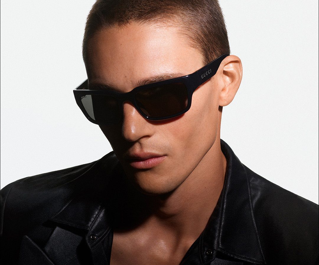 Man wearing black high fashion sunglasses and a black leather jacket.
