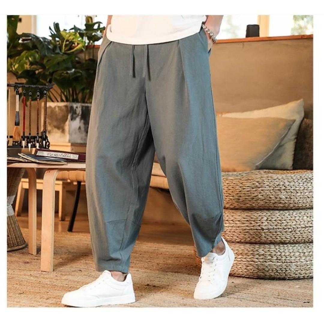 Grey-green linen drawstring pants paired with white sneakers in a bright interior.