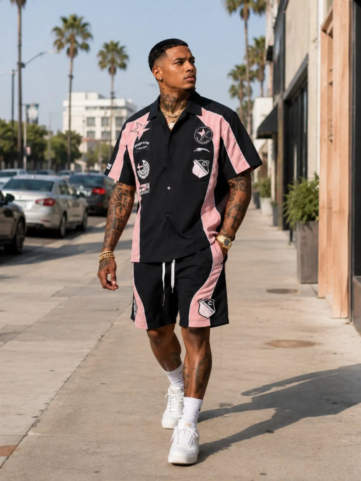 Man wearing a black and pink streetwear matching set walking on a city sidewalk